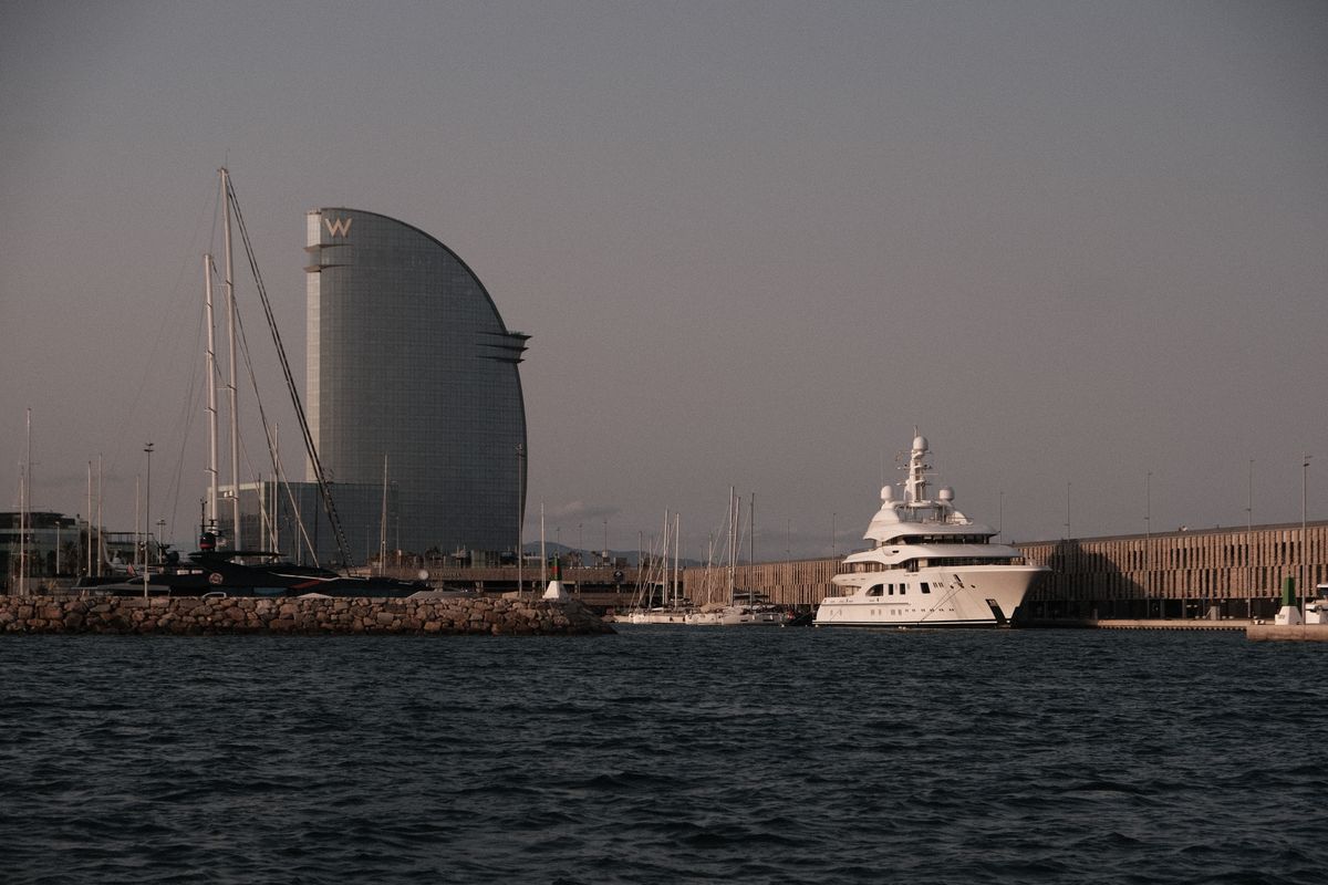 Port Vell marina at dusk with the sail-shaped W Barcelona hotel and a moored superyacht