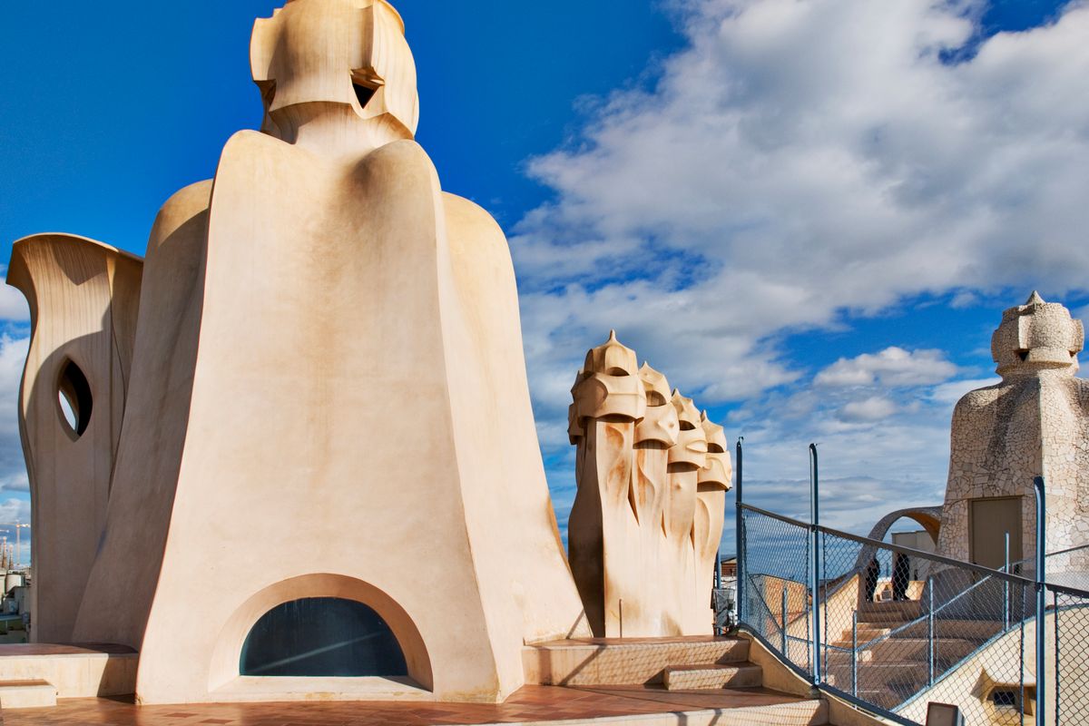 Helmeted warrior-shaped chimneys on the rooftop terrace of La Pedrera Casa Milà against a blue sky