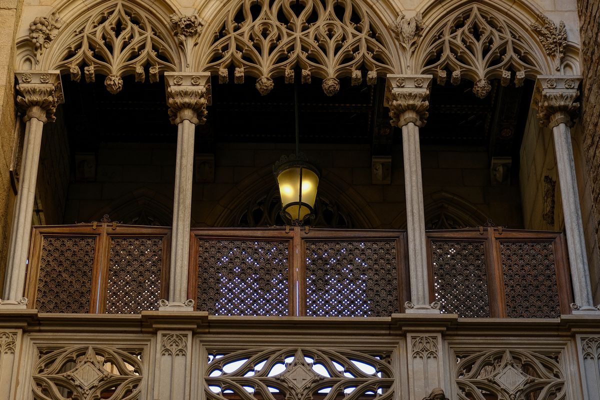 An ornate neo-Gothic spire of Barcelona Cathedral framed by a palm frond against the sky